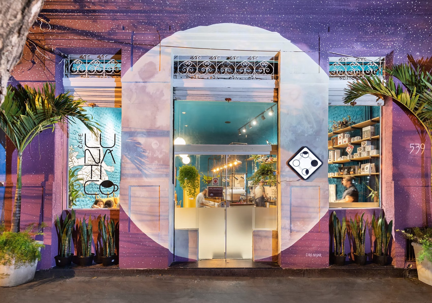 The celestial themed storefront mural and windows of Café Lunático at night